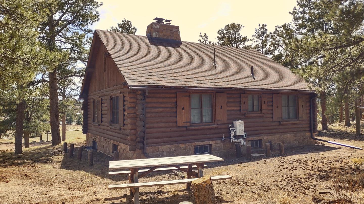 the back of a log cabin with picnic table in the foreground.Redfeather Assistant Ranger Cabin - Back of cabin showing picnic table. 