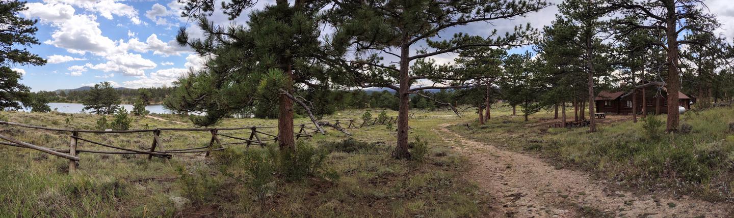 view of lake, fence, trees, trail, and log cabin in backgroundOverview showing Ranger Cabin and West Lake. 