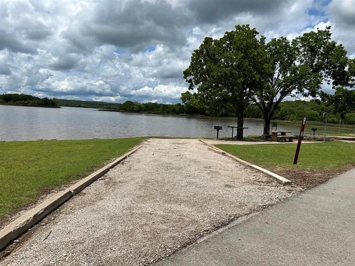 Site 7 overlooks Heyburn Lake with shade, picnic table, grill, utility table, and waterfront Site 7 entryway