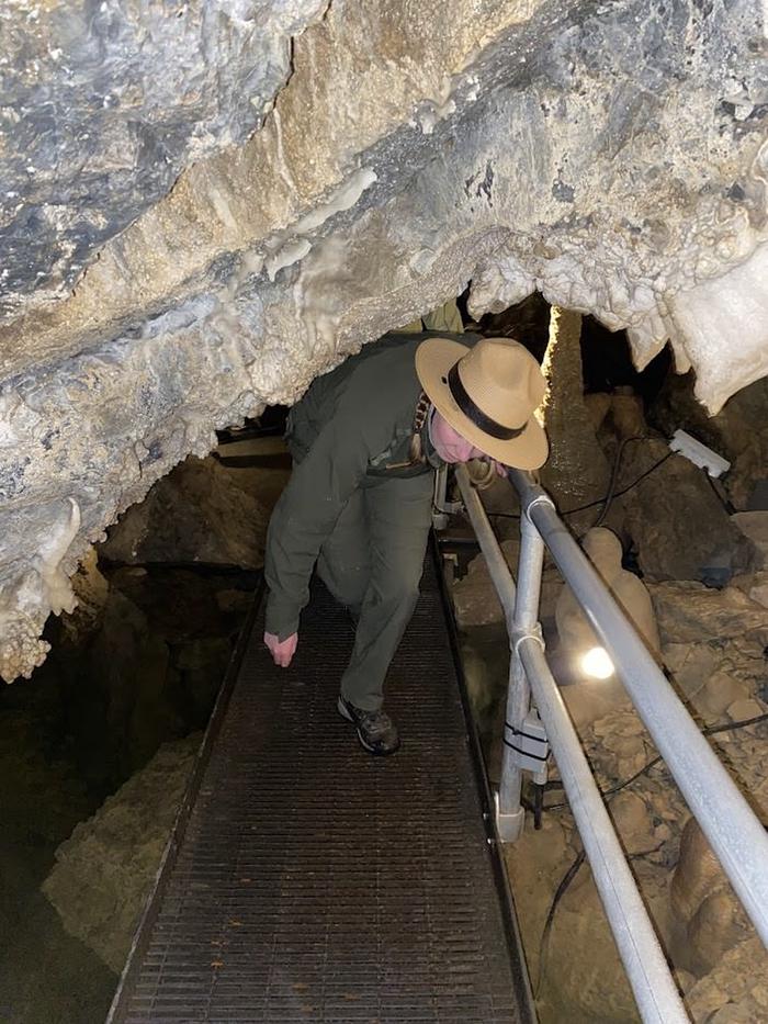 Ranger ducking under a low spot while walking across a metal walkwayRanger ducking under low spot in Middle Cave