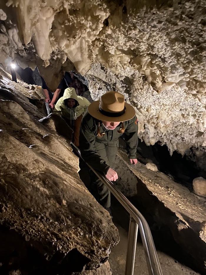Ranger and visitors duck low under a longer stretch of spikey cave formations called stalactitesLow ceilings, watch your head!