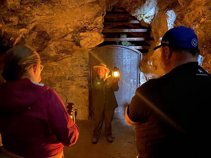 Ranger explaining how the lantern works next to the heavy wooden door leading into Hansen CaveBeginning of Historic Lantern Tour