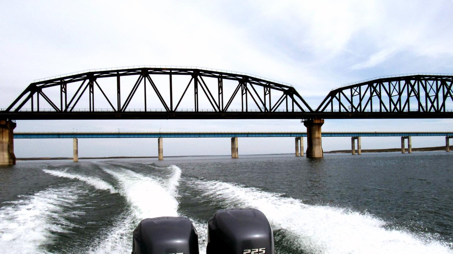 The wake behind a boat as it passes under the Highway 90 Bridge