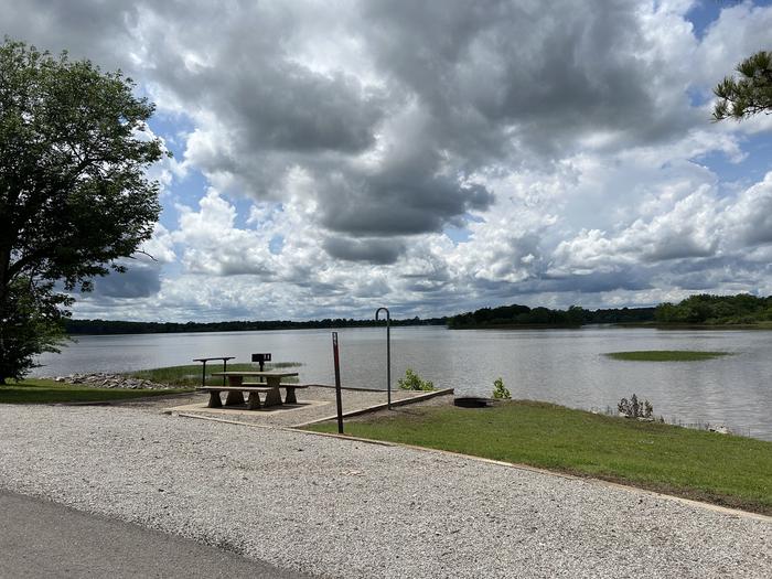 Site 2 is located along the roadway of the main road. A photo of Site 2 of Loop  at Sunset Bay with Boat Ramp, Picnic Table, Fire Pit, Tent Pad, Waterfront, Lantern Pole