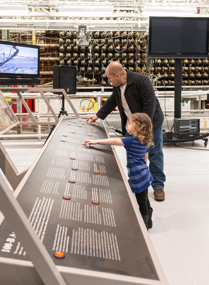 ExhibitsA dad and child look at an exhibit to learn more about the Manhattan Project.