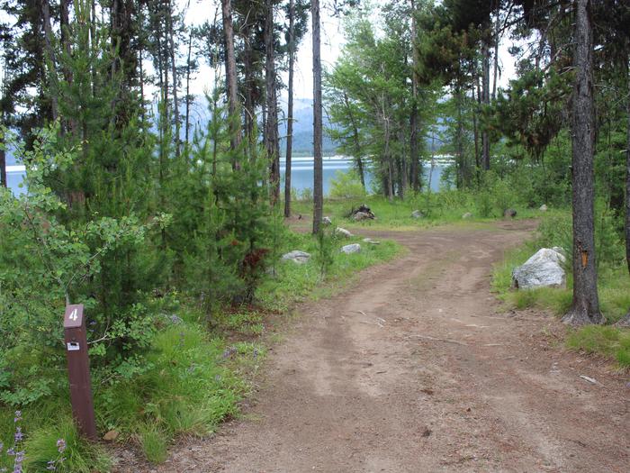 Site 4 at Barneys Campground.  A dirt trailer pull through is shown next to green trees Site 4 at Barneys Campground, Boise National Forest. Site post and trailer pull-through are shown. 