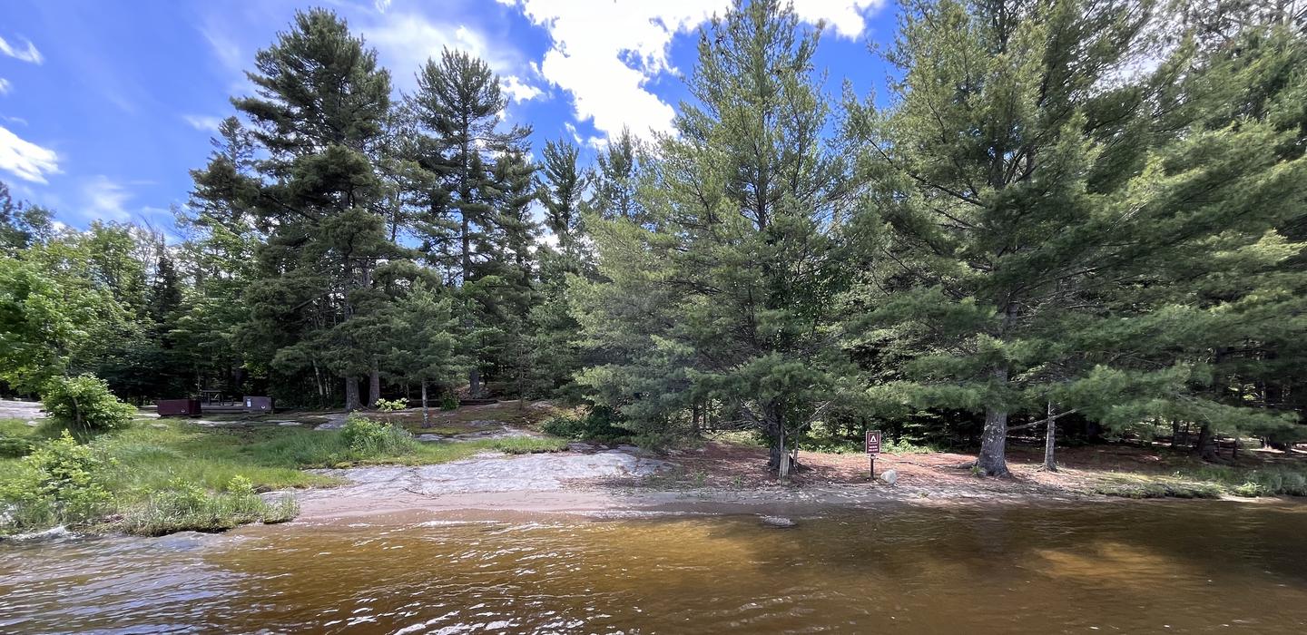 K22 - Moxie Island, view of sand landing from water with the campsite in the background on the left side of the image with large trees covering the rest.View of sand landing and campsite from water.