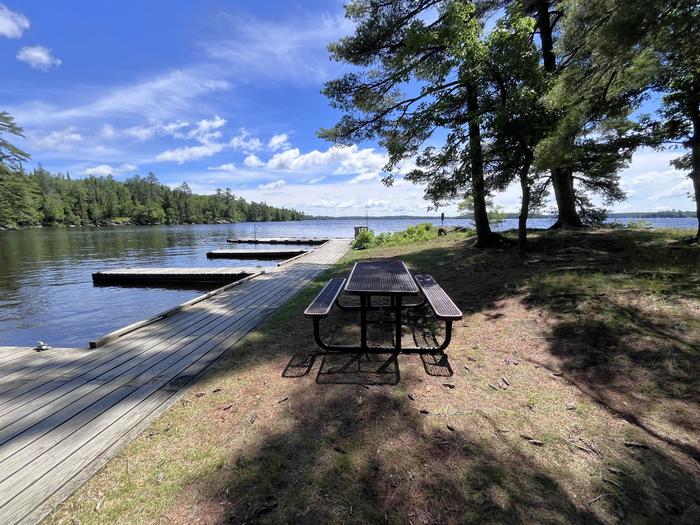 K54 - Kabetogama Lake Group Site, view of dock system from shore with a picnic table in the foreground.Dock system from shore