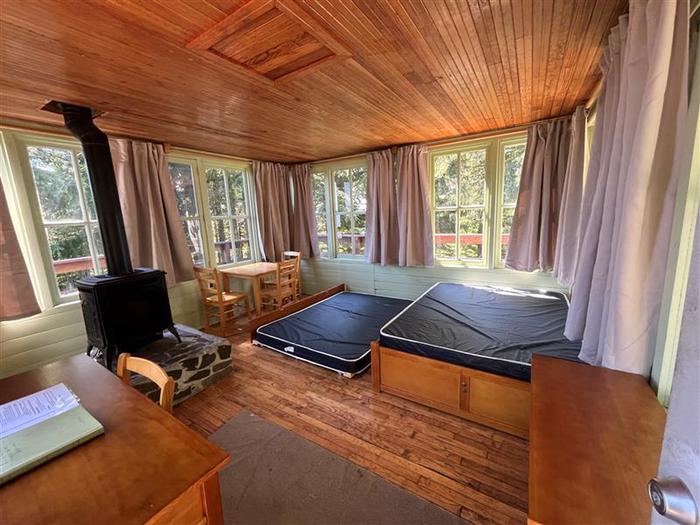 Inside of cabin with trundle bed, desk, table, and propane heater.Inside of Timber Butte cabin