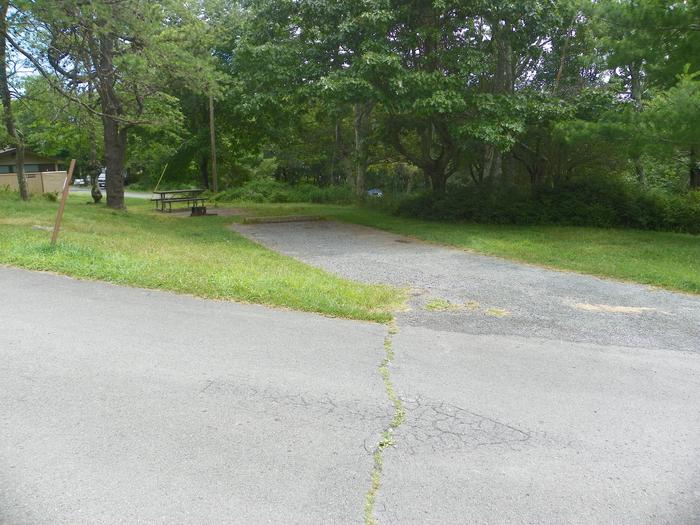 Campsite A60 has gravel driveway, grassy tent pad, picnic table, and fire ring. Restroom building in the background.