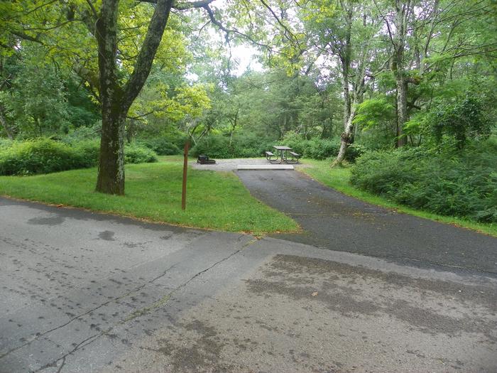 Campsite A89 has a sloped back in driveway, fire pit, picnic table, and grass tent pad. 