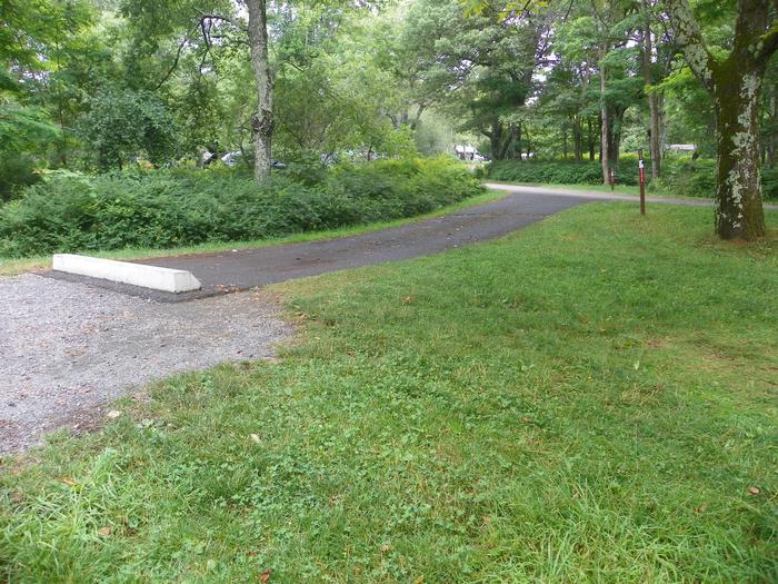 A89 driveway slopes down from the road. There is a large grass tent pad next to the driveway.