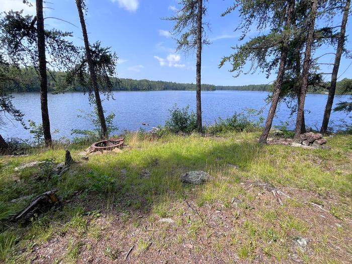 View looking out from Oslo Lake campsite with fire ring in foreground and lakeshore tree line in the distanceB12 - Olso Lake backcountry campsite fire ring and view looking west