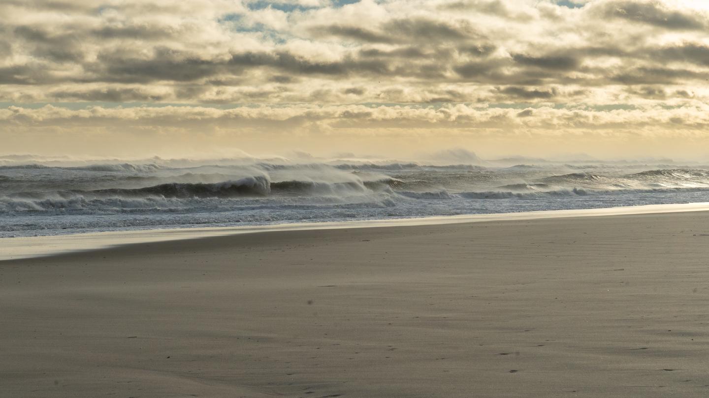 Surf after storm. Large ocean waves, beach and cloudy skies.Heavy surf after a storm on the Great South Beach on Fire Island.