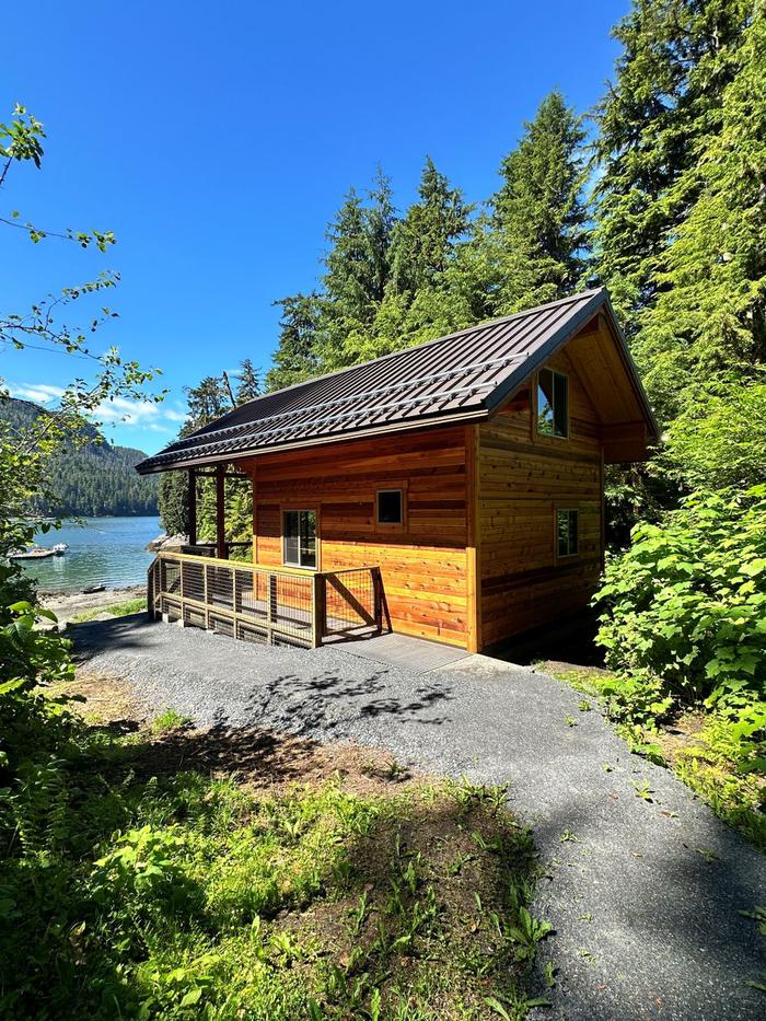 View of the side and back of Anan Bay Cabin with bay and boats in background.Side view of cabin