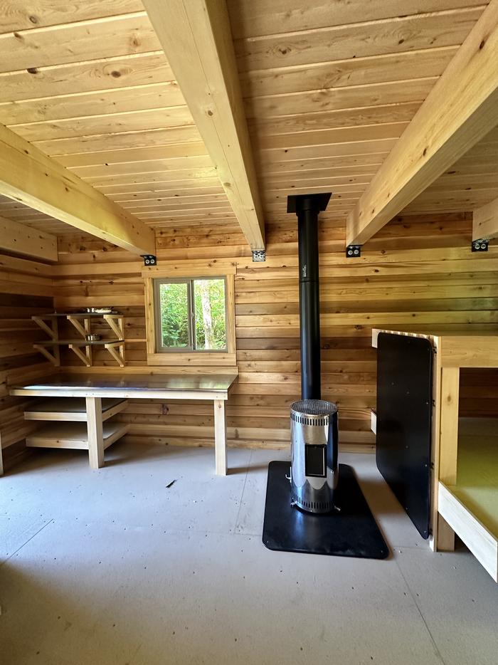 Inside of cabin showing oil stove, shelf, bunkbedInterior of cabin