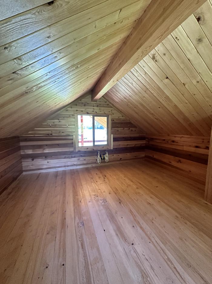 View of the loft inside the cabin with windows.Cabin loft area