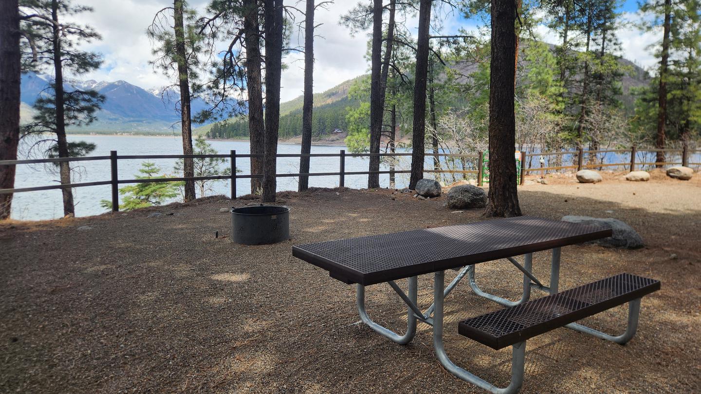 Campsite along lake with picnic table and fire ring