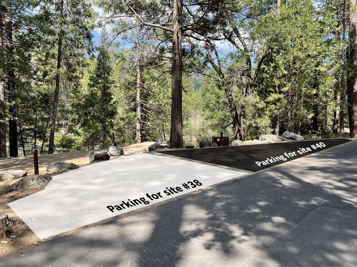 An image featuring a dirt parking area surrounded by trees next to the road. Overlayed on the parking area is a white box to illustrate the parking zone for site 38. Next to it, a black box is overlayed on the parking area to illustrate the parking area for site 40.Shared parking with site 40. 2 vehicles will fit in this parking pad. Expect vehicles to be parked close together.