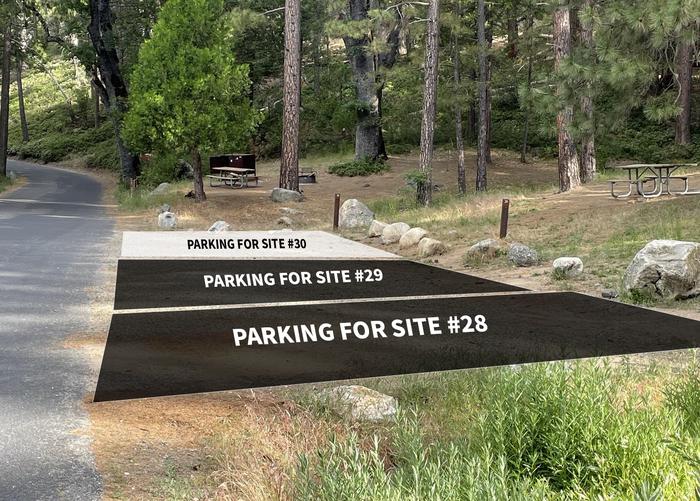 A gravel parking area is at the base of a grassy hill. 2 black boxes and 1 white box are overlayed on the image. The two black boxes indicate the parking areas for sites 28 and 29. The white box indicates the parking area for site 30Parking is shared for sites #28, #29, and #30. Parking for site #30 will fit 2 cars