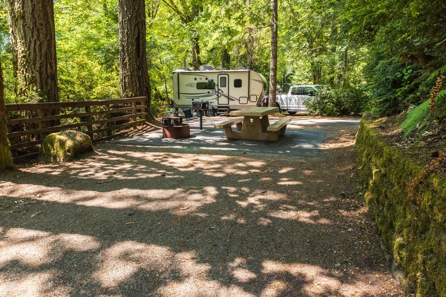 Campsite 53 tent pad, picnic table, BBQ grill, and fire pit.