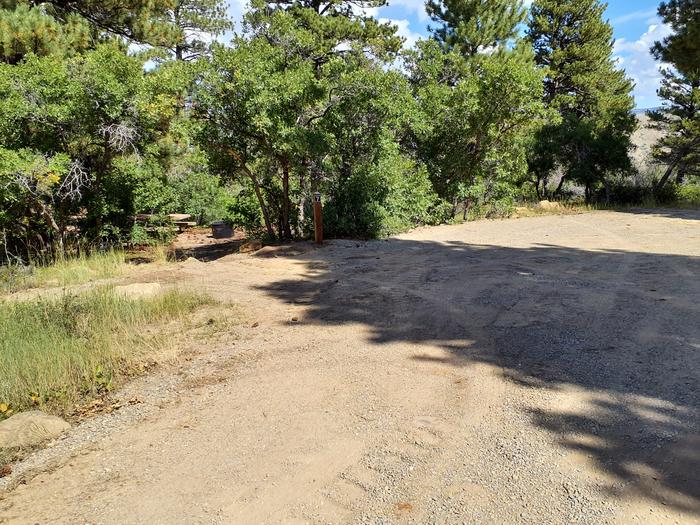 Picnic table and fire back in the trees and shoulder parkingPrice Canyon campsite 7 and parking area