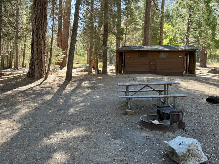 Smooth dirt tent pad surrounded by trees and near fire ring and picnic tableTent Pad
