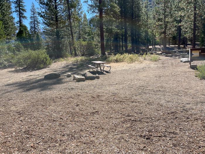 Smooth dirt tent pad surrounded by trees and near fire ring and picnic tableTent Pad
