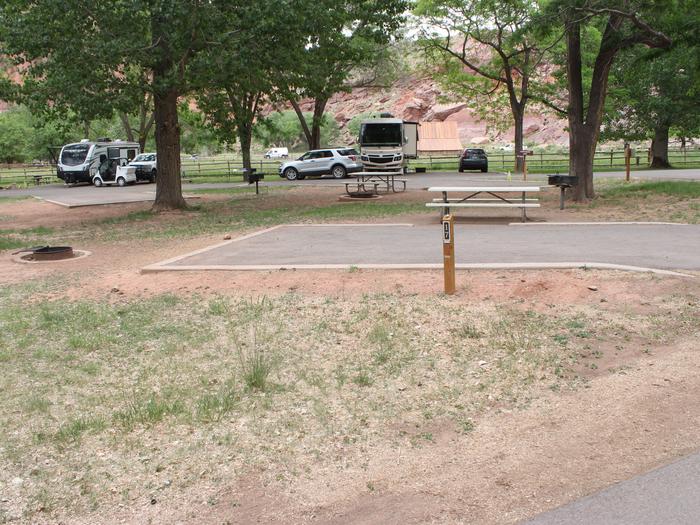 A paved driveway. Facing the end of the driveway, a fire pit is directly behind it and a picnic table and grill are off to the right. Site 17, Loop A in summer.
Paved dimensions: 14' x 29'