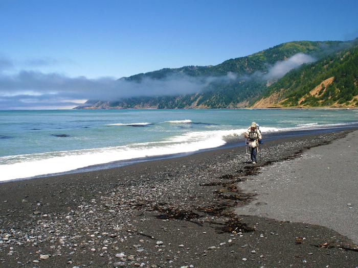 A backpacker walks along the beach in the King Range National Conservation Area.King Range National Conservation Area