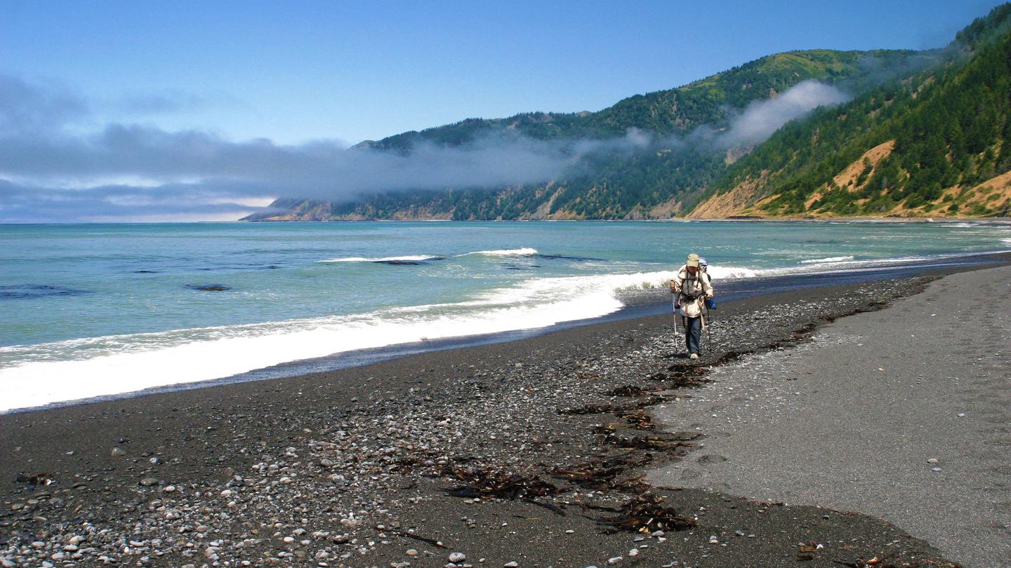 A backpacker walks along the beach in the King Range National Conservation Area.King Range National Conservation Area