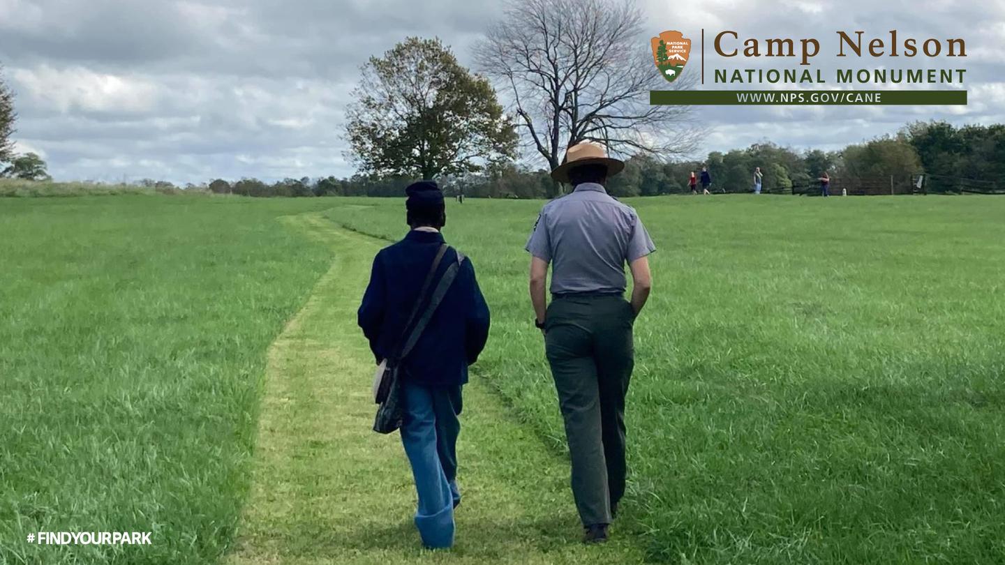 In the Footsteps of Freedom at Camp Nelson National MonumentA Park Ranger and a United States Colored Troops [USCT] soldier walking on a trail. Trees and people can be seen in the background.