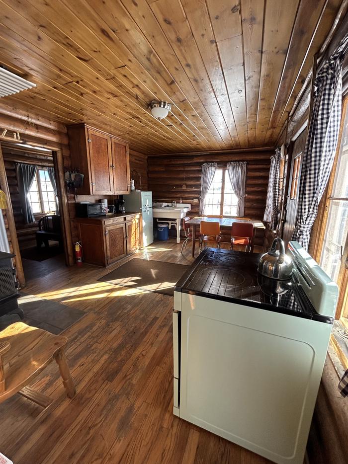 MUDDY GUARD CABIN kitchen and dining roomThe kitchen includes a refrigerator and electric cooking stove, tables and chairs, and a minimum amount of cabinetry. 