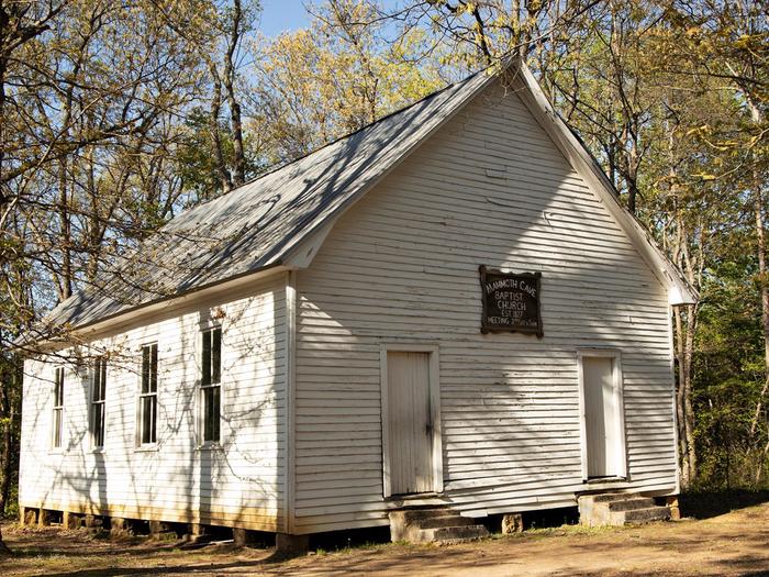 White sided building with two entrances and concrete steps leading to each entrance. The church has three windows on one side and is slightly elevated.Mammoth Cave Baptist Church
