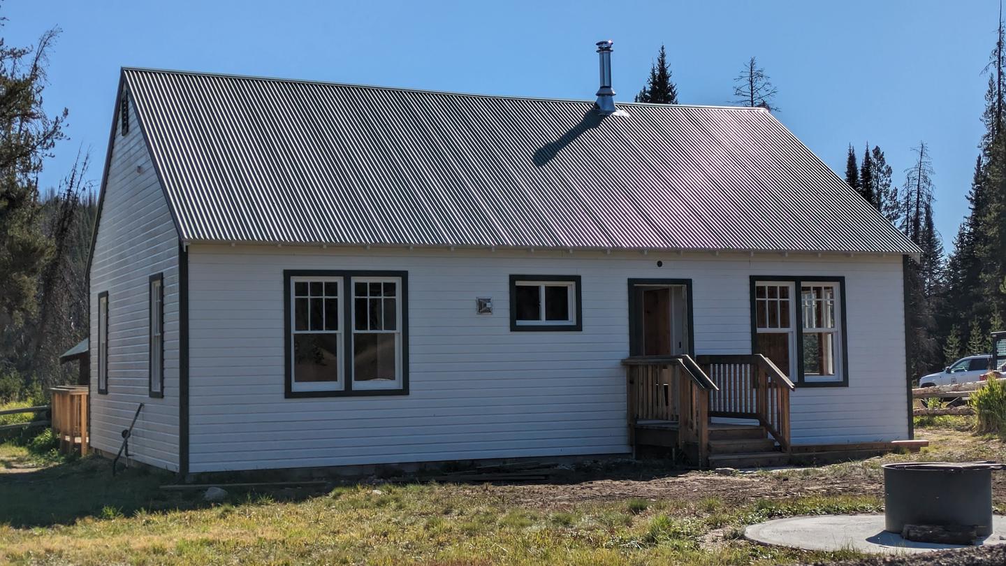 Red painted cabin with white trim and green roof. Fence along the front. Burgdorf Rental Cabin - exterior