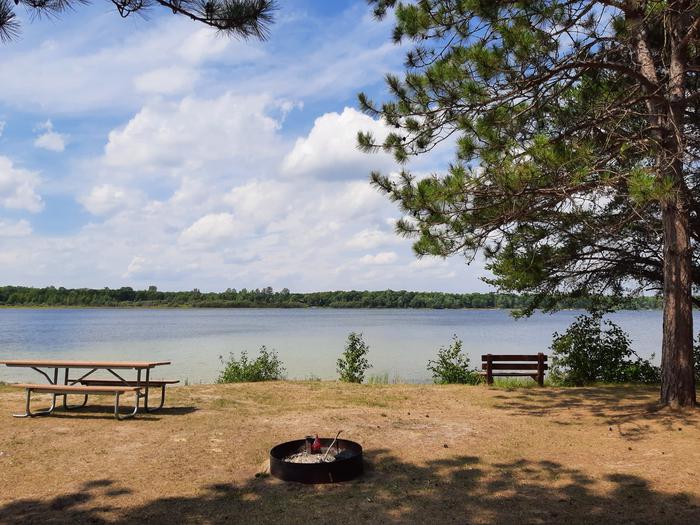 A picture of Mabel Lake with a firering, picnic table, and bench.Mabel Lake Picnic Area