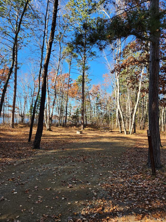 A picture of a campsite in Mabel Lake Campground with trees, a site marker, and a firering.A campsite at Mabel Lake Campground.