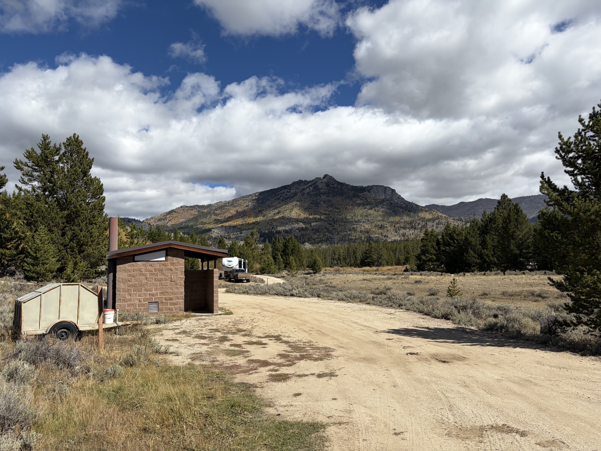 Scenic view of campground with vault toilets and trash bin