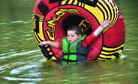 child in life jacket playing with tube