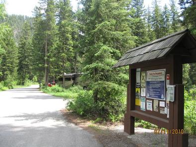 Swan Creek Entrance - Information board, road, RV and pine treesSwan Creek Campground