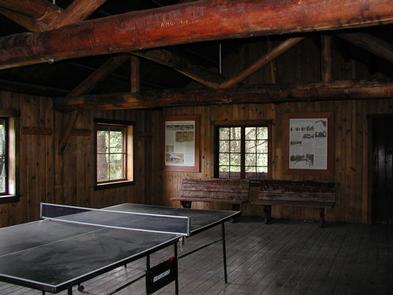 Ping-pong table in dimly lit large room with log rafters and benches.Ping-Pong table in American Ridge Lodge 