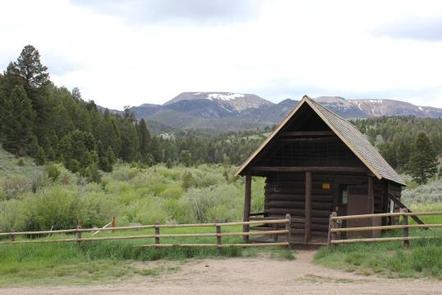  Brown forest service cabin surrounded by green trees and rolling hillsHells Canyon Guard Station