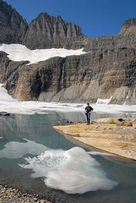A man views rock cliffs above an alpine lake near Many GlacierA man views rock cliffs above an alpine lake