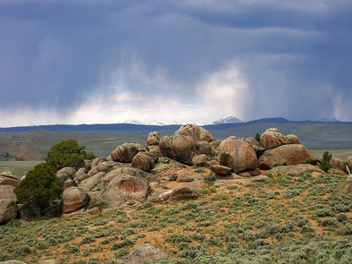 Boulder Lake Recreation AreaLarge red granite boulders stand on top of a butte in front of a thunderstorm in the distance.
