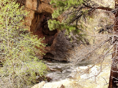 Outlaw CaveA cave stands above a raging river with white caps.